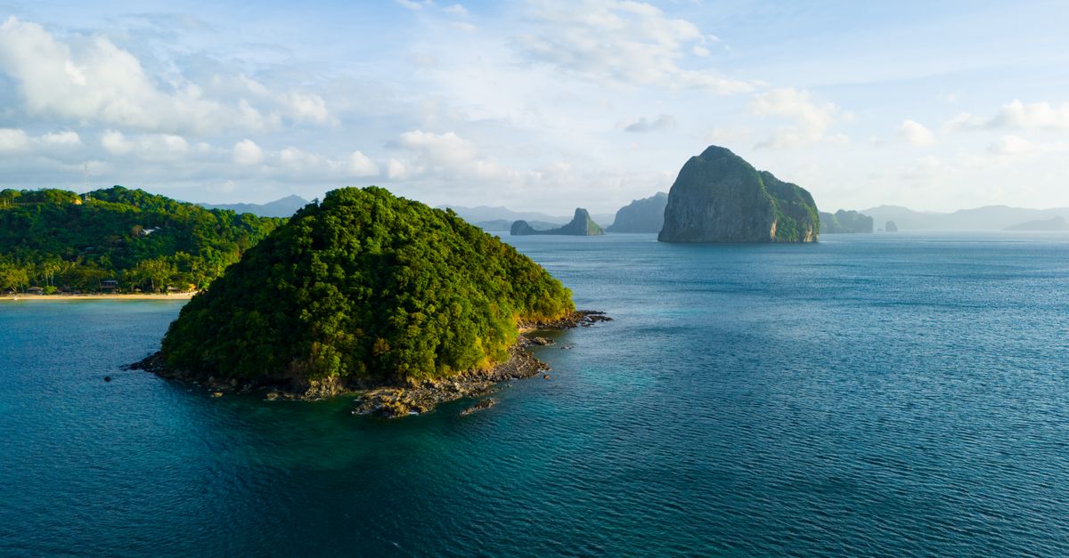 A breathtaking aerial view of the lush green islands of El Nido, Philippines, surrounded by crystal blue waters.